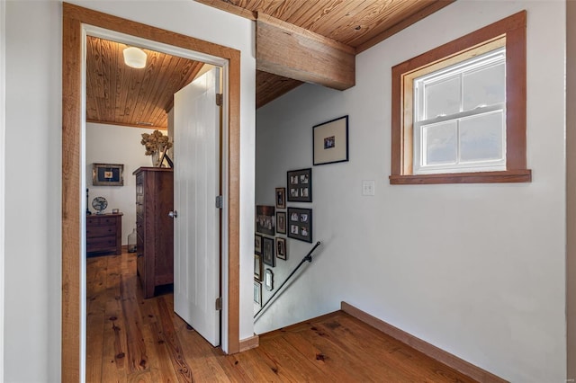 corridor with an upstairs landing, beam ceiling, wooden ceiling, and wood-type flooring