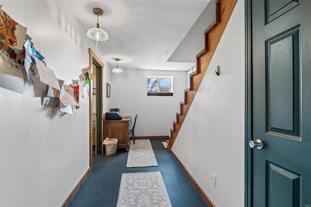 hall featuring concrete floors, baseboards, and stairs