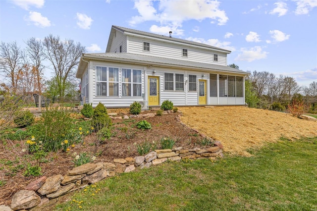 back of house featuring a lawn, a sunroom, and metal roof
