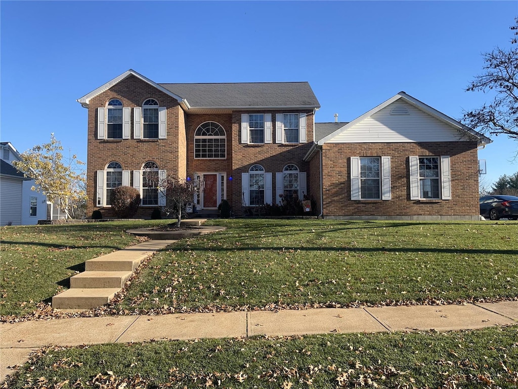 view of front of home with a front yard and brick siding