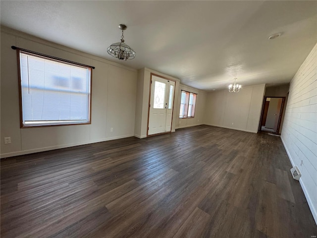 unfurnished room featuring a notable chandelier, baseboards, visible vents, and dark wood-style flooring