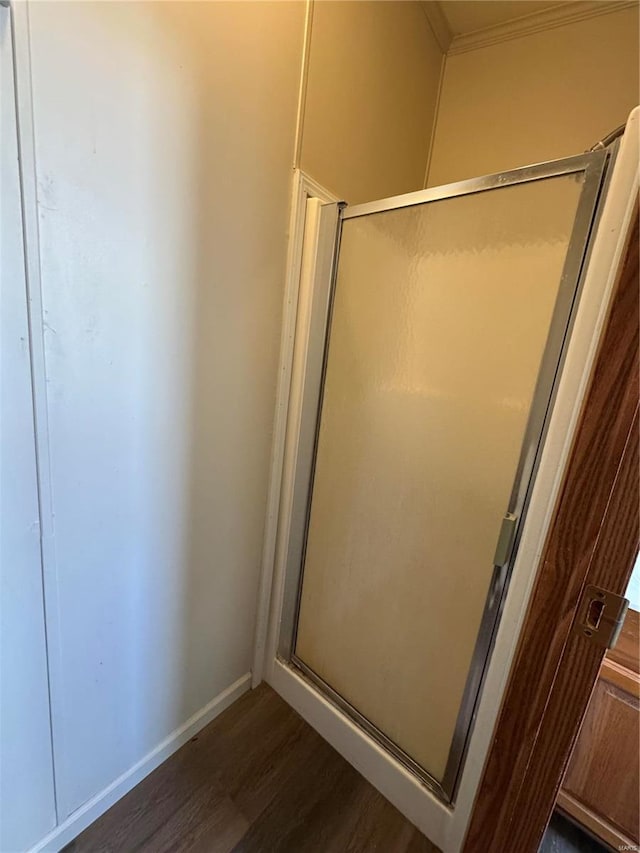 bathroom featuring a stall shower, baseboards, wood finished floors, and ornamental molding