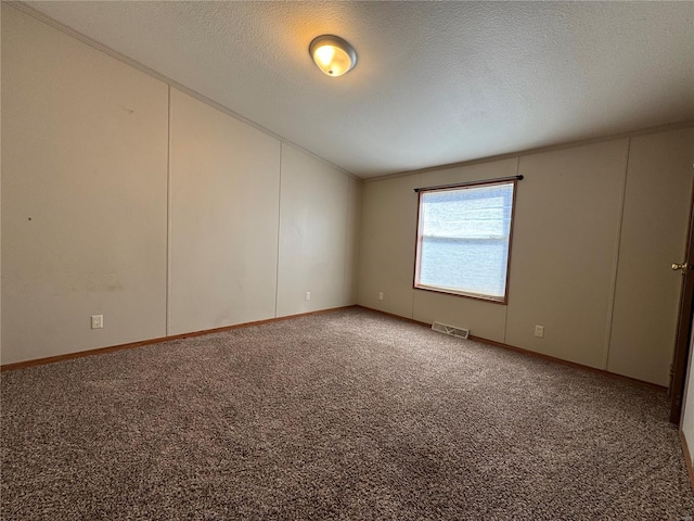 unfurnished room featuring visible vents, lofted ceiling, carpet, and a textured ceiling