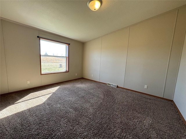 unfurnished room with lofted ceiling, visible vents, carpet floors, and a textured ceiling