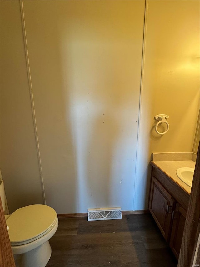 bathroom with vanity, toilet, wood finished floors, and visible vents