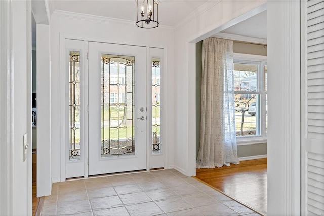 entrance foyer with baseboards, an inviting chandelier, crown molding, and light wood finished floors