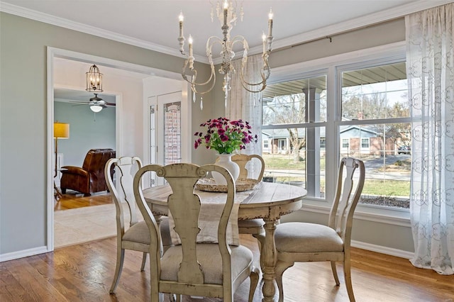 dining room with ceiling fan with notable chandelier, wood finished floors, baseboards, and ornamental molding