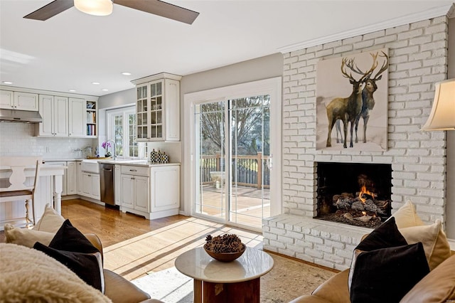 living area with recessed lighting, a fireplace, a ceiling fan, and light wood-style floors