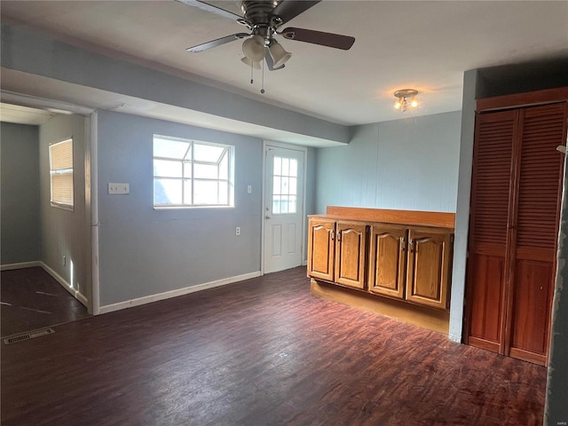 interior space with visible vents, brown cabinets, dark wood-type flooring, baseboards, and ceiling fan