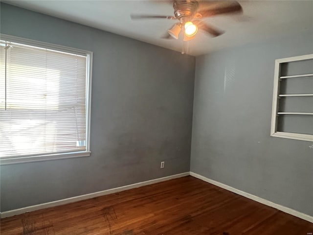 unfurnished room with ceiling fan, baseboards, built in shelves, and wood finished floors