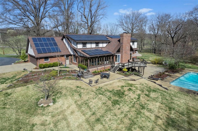 back of property with roof mounted solar panels, a patio, and a yard