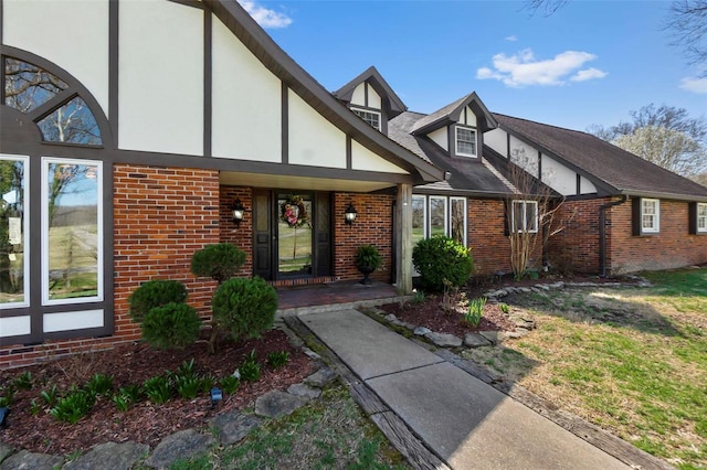 view of front of property with covered porch, brick siding, and stucco siding