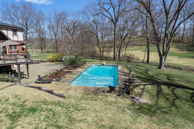 pool with a lawn, a diving board, and a patio area