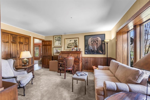 living room featuring wood walls, wainscoting, and light carpet