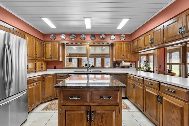 kitchen featuring a sink, brown cabinetry, light tile patterned floors, and freestanding refrigerator