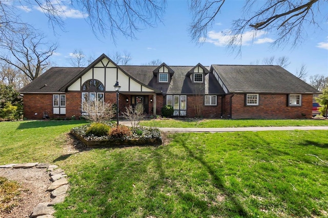 english style home with a front yard and brick siding