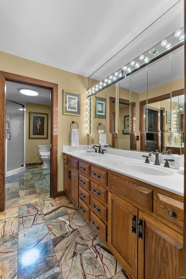 bathroom with double vanity, toilet, baseboards, and a sink