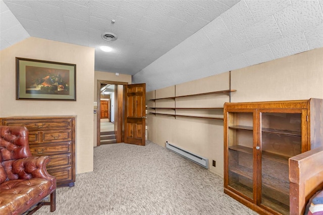 interior space featuring carpet floors, vaulted ceiling, visible vents, and a baseboard heating unit