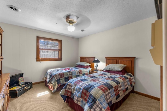 carpeted bedroom featuring baseboards, a textured ceiling, visible vents, and a ceiling fan