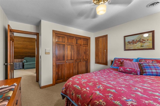 carpeted bedroom featuring baseboards, a textured ceiling, visible vents, a ceiling fan, and a closet