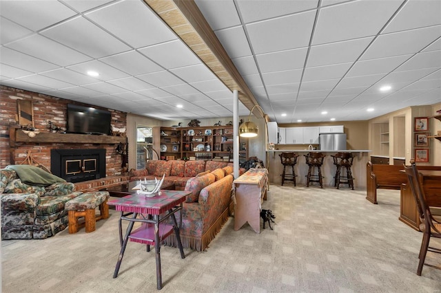 living area with light colored carpet, a fireplace, recessed lighting, and a paneled ceiling