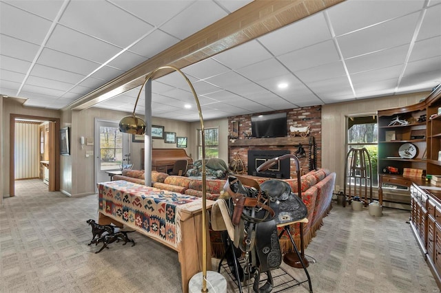carpeted living room with a brick fireplace and a drop ceiling