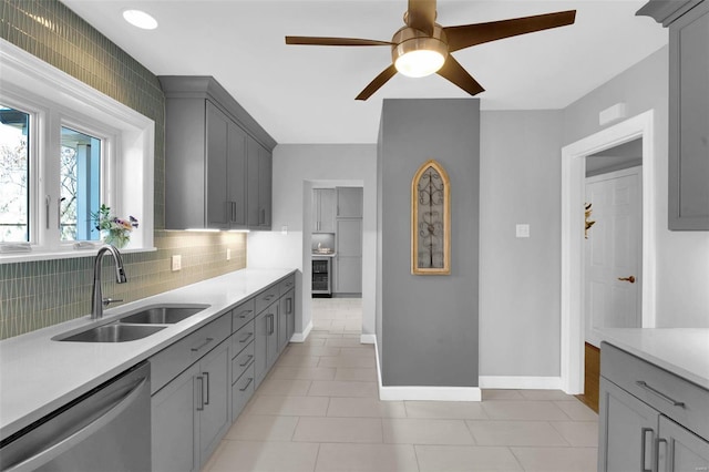 kitchen featuring dishwasher, light countertops, gray cabinetry, and a sink