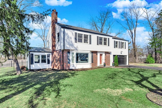 view of front of home with a front yard, fence, a chimney, aphalt driveway, and brick siding