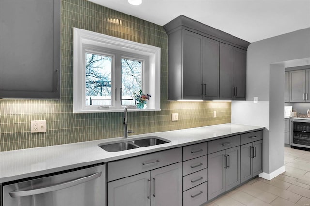 kitchen featuring beverage cooler, a sink, gray cabinetry, and stainless steel dishwasher