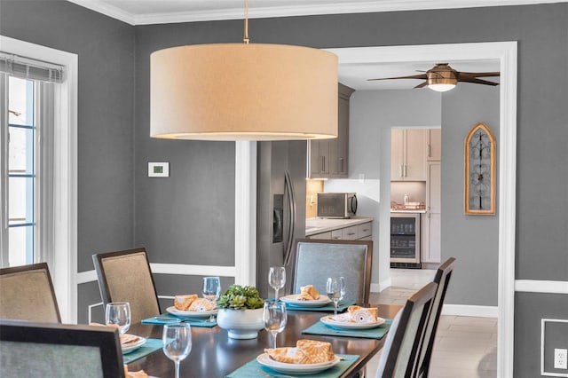 dining space featuring ceiling fan, baseboards, beverage cooler, and crown molding