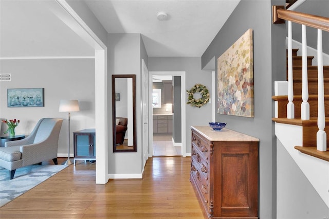 corridor featuring stairway, baseboards, and light wood-style floors