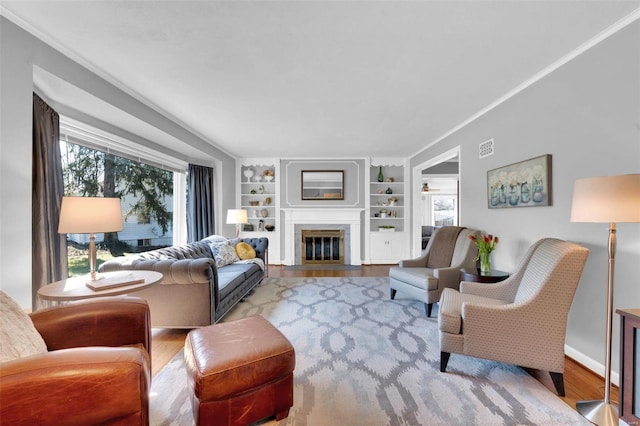 living room with crown molding, a fireplace with flush hearth, and wood finished floors