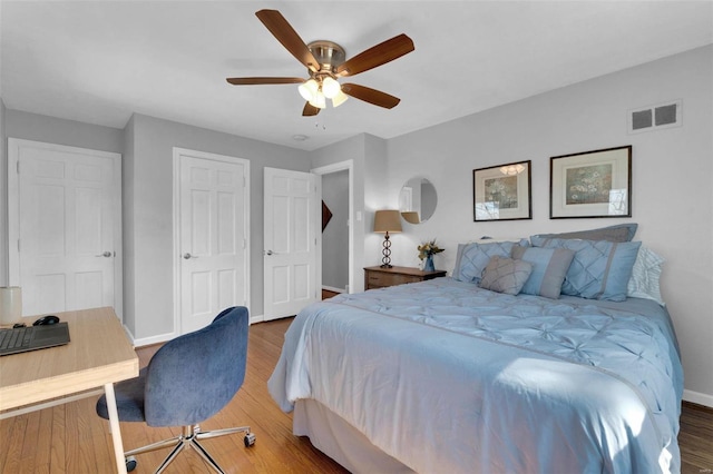 bedroom with visible vents, baseboards, wood finished floors, a closet, and a ceiling fan