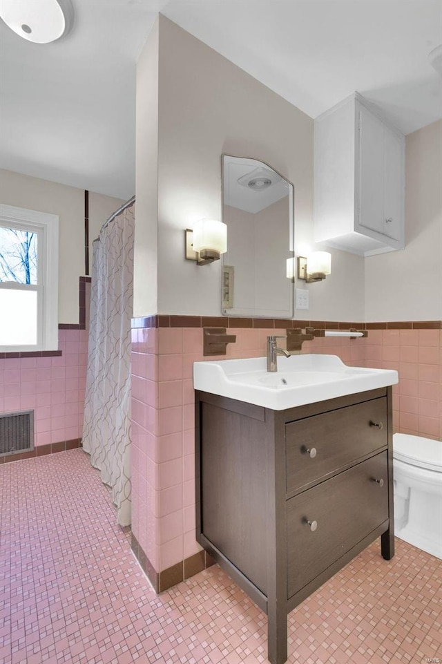 full bathroom featuring vanity, a wainscoted wall, visible vents, tile walls, and toilet