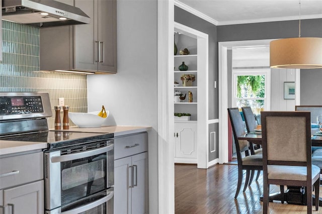 kitchen with crown molding, under cabinet range hood, range with two ovens, gray cabinets, and dark wood-style flooring