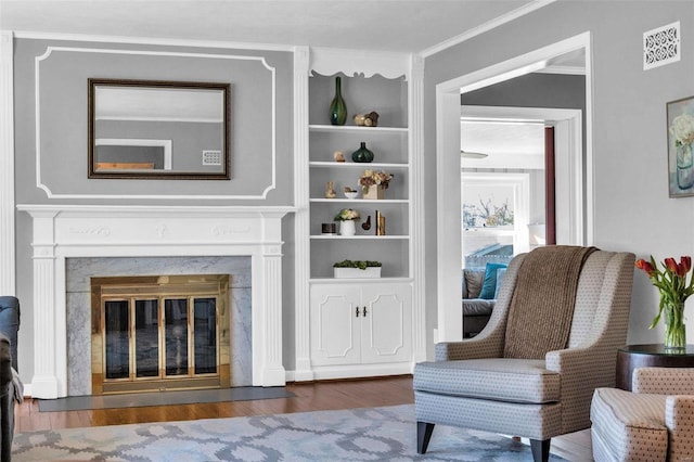 sitting room featuring a premium fireplace, visible vents, wood finished floors, and crown molding