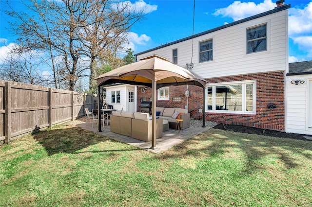 rear view of property featuring a patio, a fenced backyard, brick siding, and an outdoor hangout area