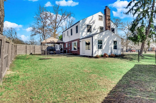 back of property featuring a yard, brick siding, a fenced backyard, and a chimney