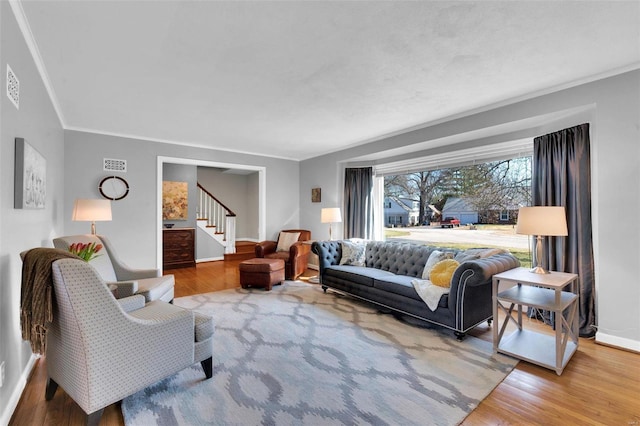 living area with visible vents, ornamental molding, wood finished floors, stairway, and baseboards