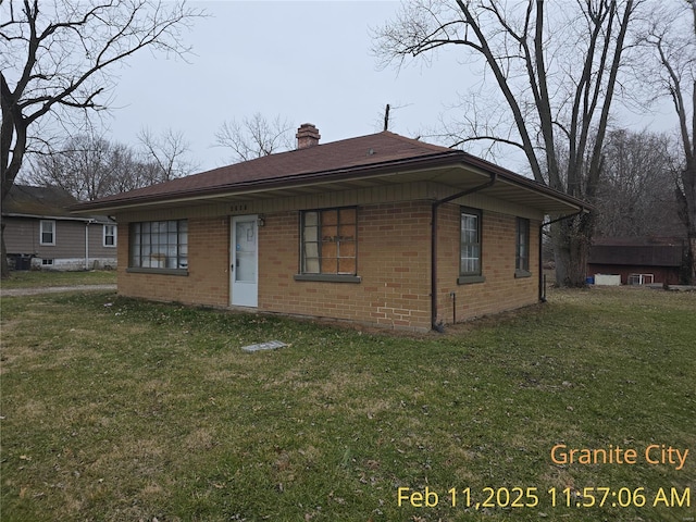 bungalow-style house with brick siding, a chimney, and a front yard