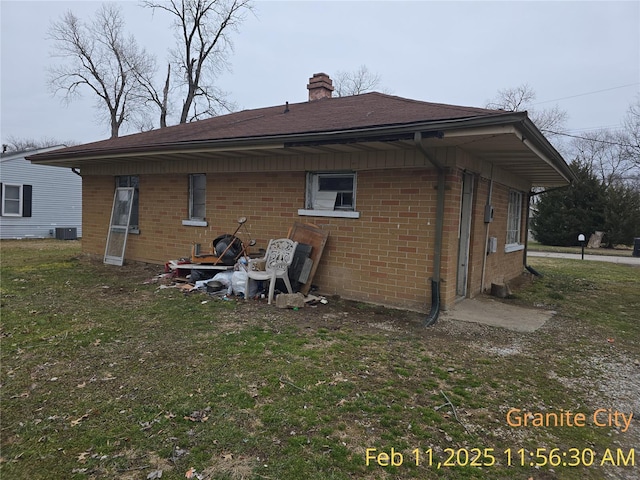 back of property featuring a yard, brick siding, cooling unit, and a chimney