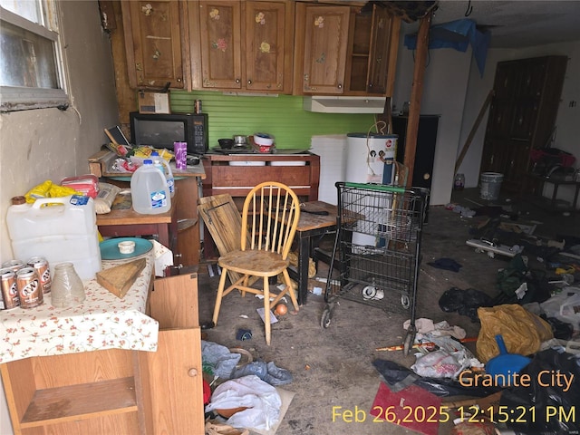 kitchen with brown cabinetry, water heater, and black microwave