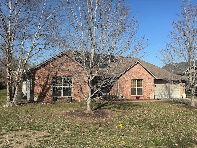 ranch-style house featuring a garage, brick siding, and a front yard