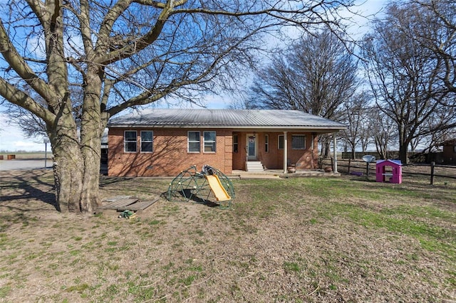 view of front of home with a front lawn, fence, brick siding, and metal roof