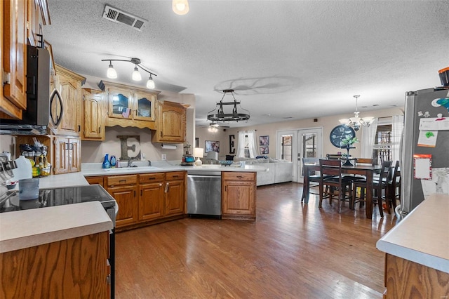 kitchen with visible vents, a sink, wood finished floors, appliances with stainless steel finishes, and a peninsula