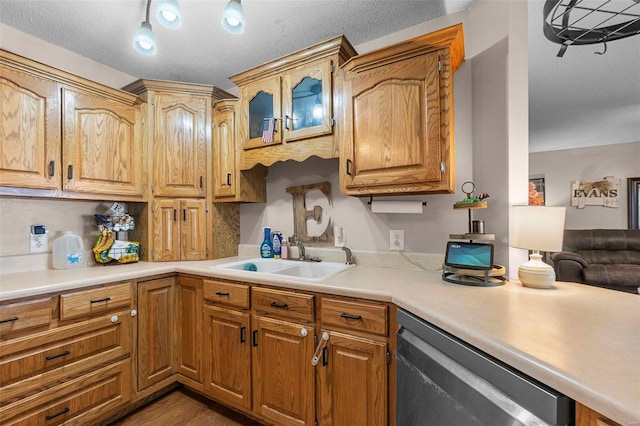 kitchen with a sink, light wood-style floors, light countertops, glass insert cabinets, and dishwasher