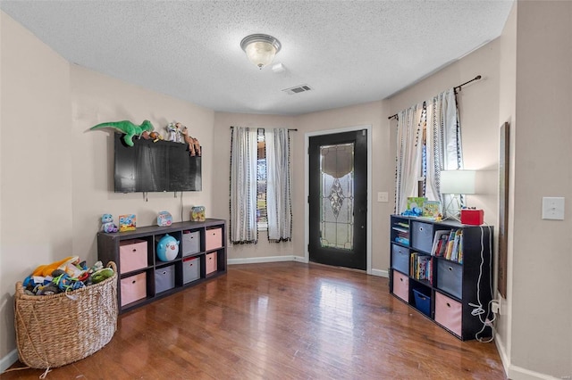 entrance foyer with visible vents, a textured ceiling, baseboards, and wood finished floors