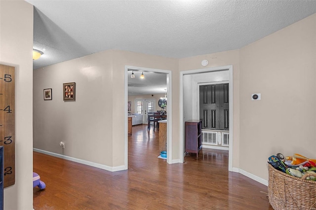 corridor with wood finished floors, baseboards, and a textured ceiling