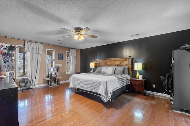 bedroom featuring a textured ceiling, wood finished floors, visible vents, and baseboards