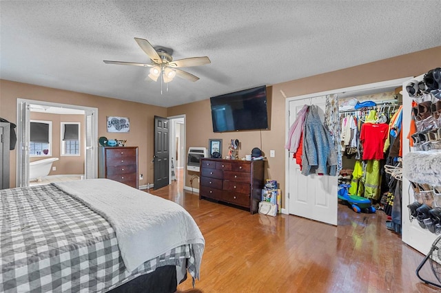 bedroom with wood finished floors, baseboards, ceiling fan, a closet, and a textured ceiling